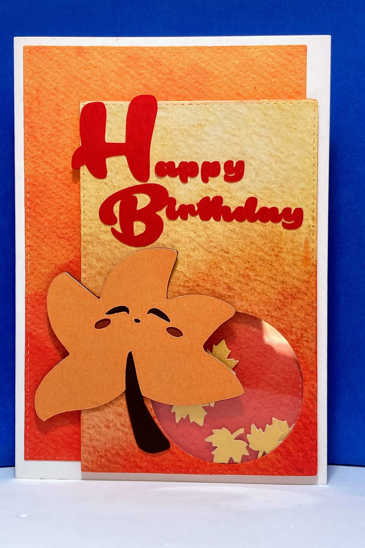 Handmade kawaii autumn leaf birthday shaker card with red Happy Birthday greeting and circular leaf window.