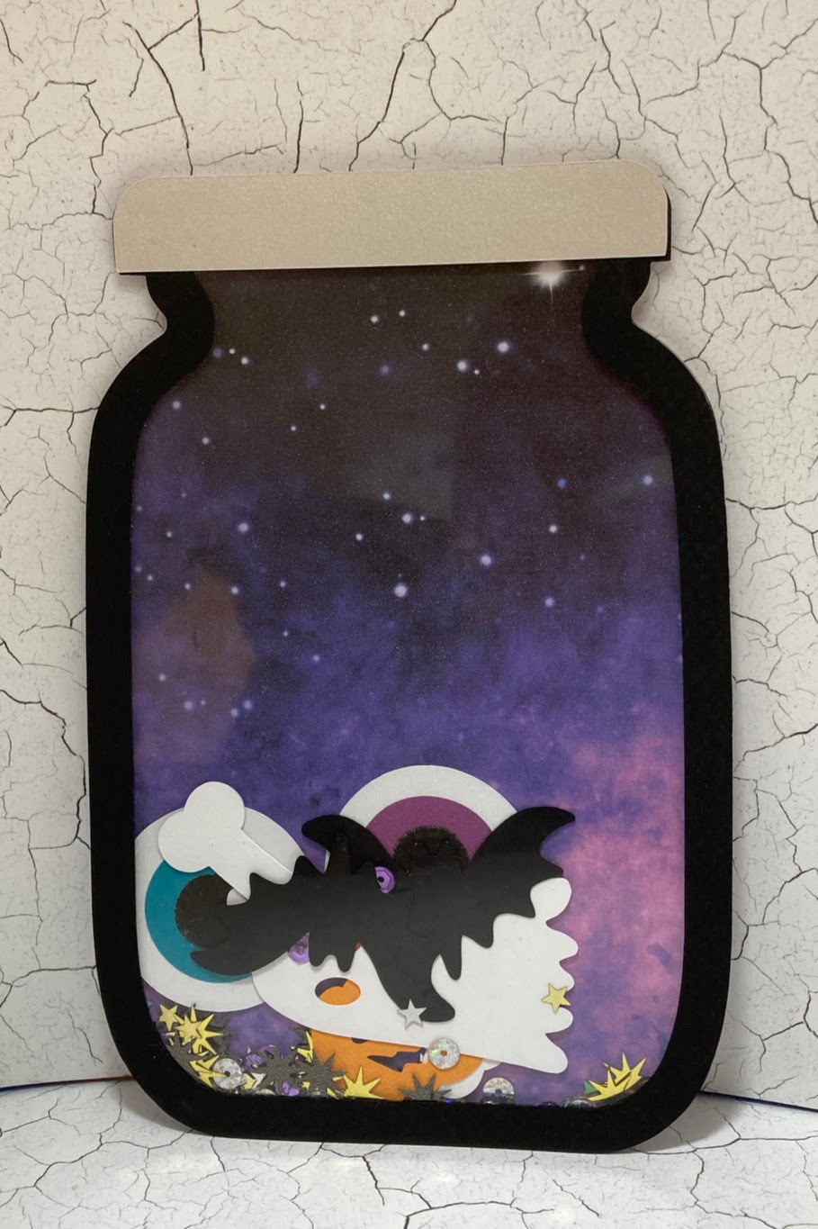 Purple jar-shaped Halloween shaker with a bat, ghost, eyeballs and star sequins.