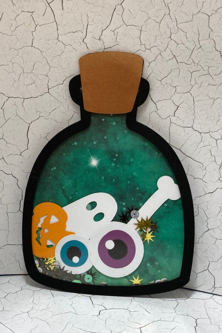 Rounded green potion bottle shaker with a ghost, pumpkin, eyeballs and sequins.